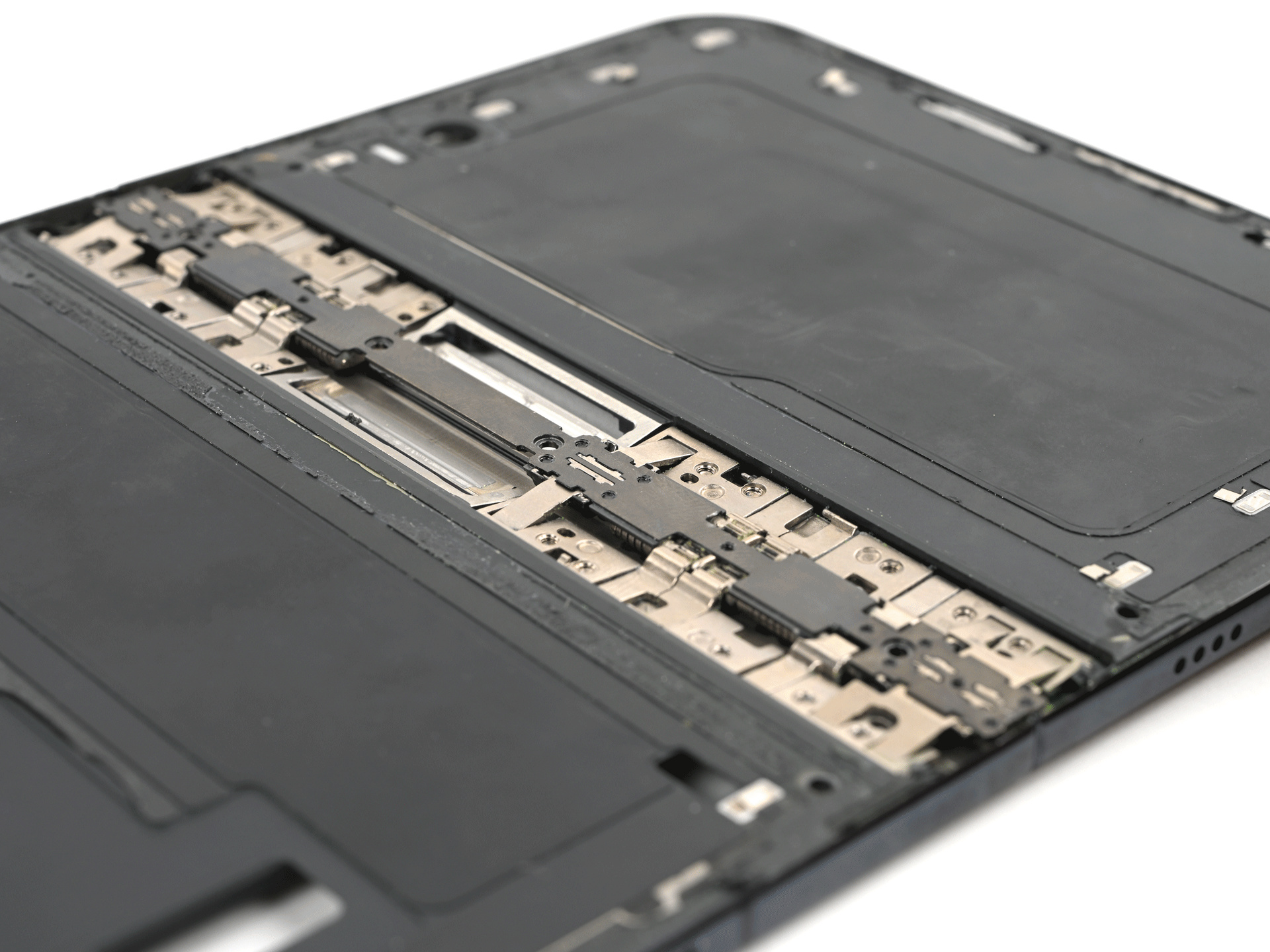 Close-up, at an angle, of an opened iPhone Duo with its inner screen removed, showing interlocking metal hinge links and plates running across the middle of the dark frame.